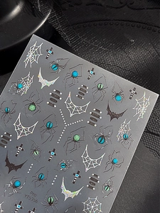 Macro shot of Halloween spider nail stickers with holographic webs and gemstone details
