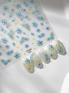Macro view of blue daisy nail art stickers and floral application on white pearl nails