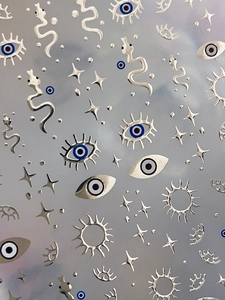 Macro view of metallic evil eye, snake and star embossed 3D nail art stickers