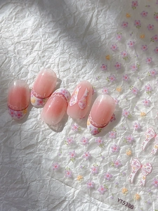 Detailed view of pink gradient nail tips with floral and bow sticker designs