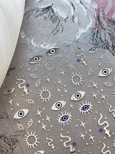 Macro shot of 3D metallic nail stickers with evil eye, sun, and star patterns