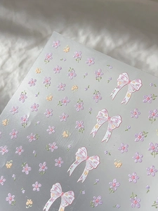 Detailed view of floral nail stickers with purple flowers and pink bow patterns