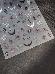 Close-up of gothic nail stickers featuring black spiders, webs and bats in dark style