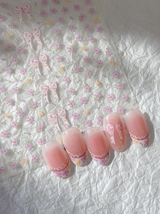 Detailed macro of floral nail decals featuring pink bows and 3D flower pattern embellishments