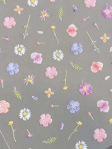 Detailed macro view of embossed floral nail art stickers featuring daisies and orchids