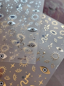 Macro detail of metallic gold and silver nail art stickers with eye and star patterns