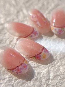 Close-up of pink gradient press-on nails with delicate purple and yellow floral patterns