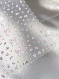 Detail view of floral nail stickers with bows and butterflies on white faux fur background