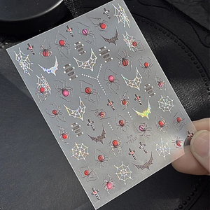 Holographic Halloween nail stickers with spiders and webs on a dark textured background