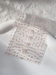 Detail of floral nail sticker with pink bows and purple flowers on transparent backing