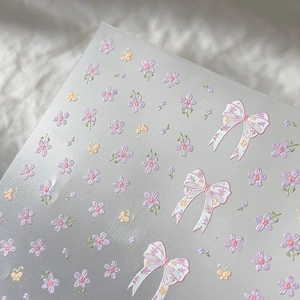 Floral bow nail art stickers featuring purple flowers and butterflies on white faux fur