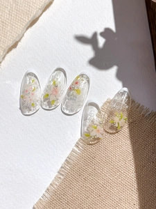 Detail of floral nail art decals with white pearls and French tips on linen texture