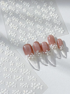 Detail von 5D-geprägten weißen Blumen-Nagelstickern mit strukturierten 3D-Blüten
