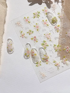 Macro detail of 3D embossed floral nail stickers with white bows and green leaves