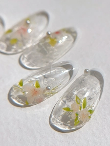 Macro detail of transparent resin nails with hand-painted cherry blossoms and micro pearls