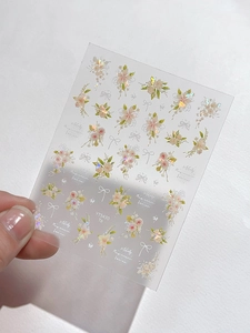 Detailed close-up of iridescent floral nail stickers with pink bouquet and white bow designs