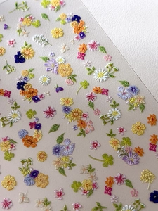 Macro detail of embossed Monet garden floral nail stickers with 3D texture and flowers