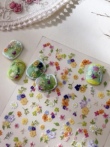 Detail of 3D embossed floral nail stickers featuring Monet garden daisy and clover designs