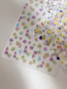 Macro detail of 3D embossed floral nail stickers in pastel colors and romantic lace