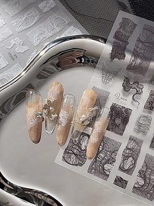 Detailed lace nail stickers with pearls, bow charms, and rhinestones on a metal tray