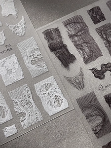 Macro shot of 3D textured lace nail stickers in black and white with vintage patterns