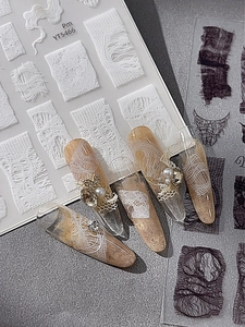 Close-up of lace nail stickers with pearl and rhinestone accents on nude nails