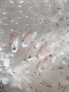 Macro shot of shell butterfly press-on nails with floral patterns and silver rhinestones