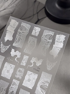 Detail shot of white lace and smoke pattern nail stickers on a transparent sheet