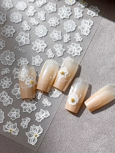 Macro detail of 3D embossed white floral nail stickers on pink gradient manicure nails