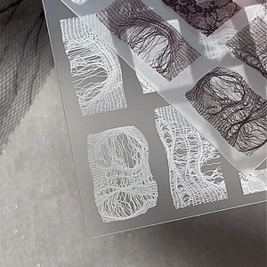 Elegant white lace nail art stickers with intricate floral and mesh patterns on a grey background