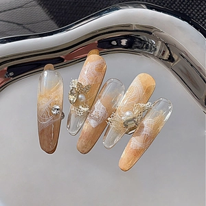 Amber gradient lace press-on nails with golden butterfly and rhinestones in silver tray