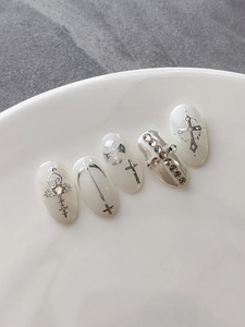 Macro view of white gothic nail art with silver cross motifs and rhinestone accents