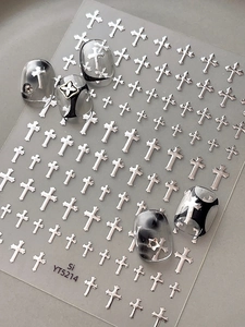 Macro detail of 3D gothic silver cross nail art stickers with metallic embossed texture