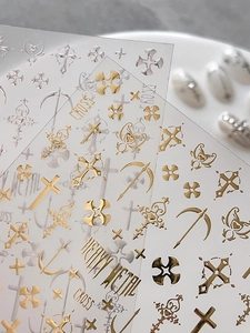 Macro detail of metallic gold and silver nail stickers with gothic cross and bow designs
