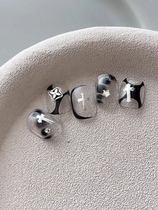 Macro shot of silver gothic crosses and black abstract lines on transparent press-on nails