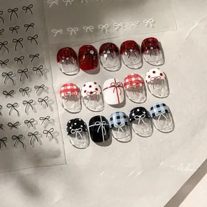 Close-up of bow nail stickers featuring red plaid and polka dots on beige background