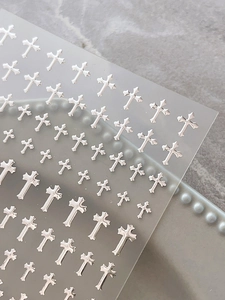 Macro shot of silver chrome cross nail art decals with metallic finish on transparent film
