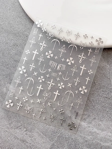 Detailed view of silver cross and gothic heart 3D embossed nail art stickers on sheet