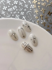 Detailed view of silver metallic cross nail stickers and rhinestone gothic charms
