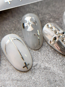 Macro detail of gothic cross nail art decals and silver chrome rhinestones