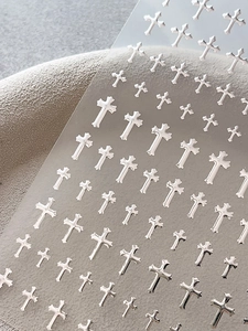 Close-up of silver cross nail art stickers with metallic texture on transparent backing