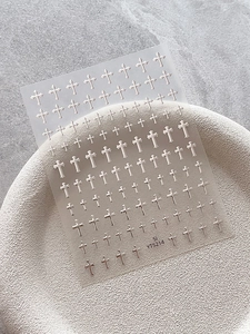 Detailed close-up of 3D embossed silver cross nail art stickers on a ceramic tray