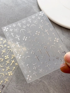 Macro detail of gothic metal nail stickers with silver and gold cross and heart designs