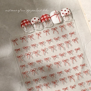 Detailed view of red bow nail stickers with checkered and polka dot nail art patterns