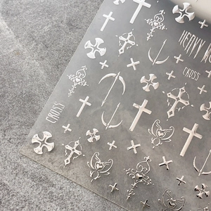 Silver gothic nail stickers with metallic embossed cross and heart motifs on stone background