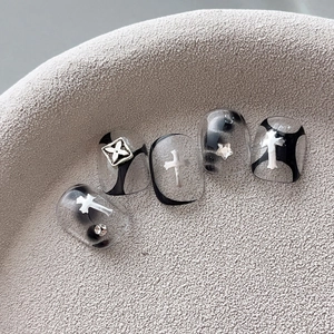 Silver gothic cross and star charms on geometric nail art tips with semi-transparent base