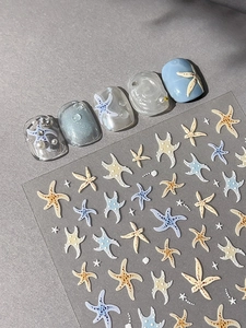 Detail of 3D starfish nail art stickers with pearl accents on gradient blue nails