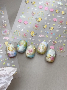 Dettaglio di adesivi nail art con uccelli e fiori a rilievo su unghie occhio di gatto