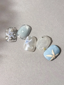 Detailed view of embossed starfish, pearls, and water droplets on ocean themed press-on nails