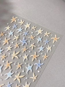 Detail shot of 3D embossed starfish nail art stickers in soft blue and beige colors